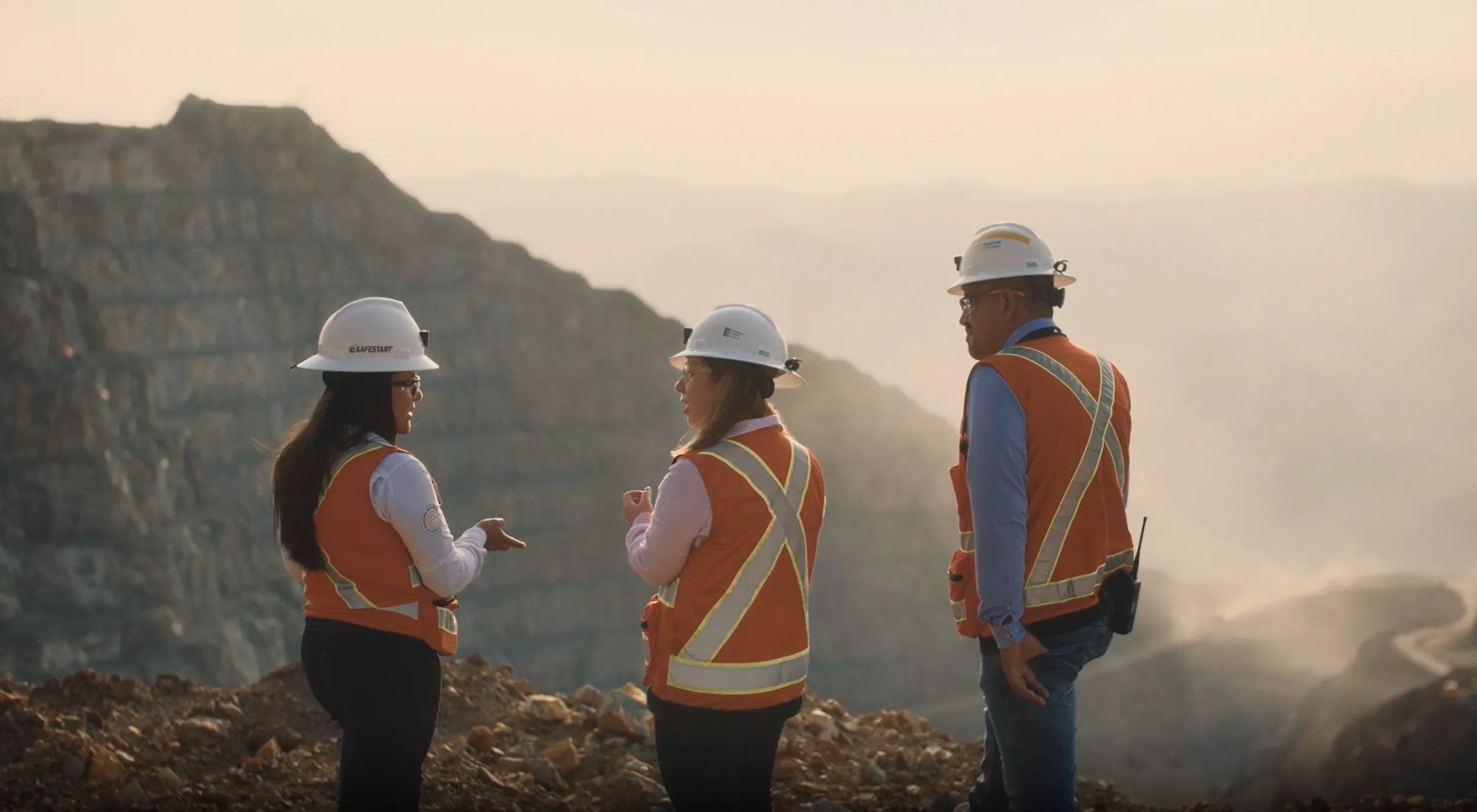 three people wearing hi-visibility clothing outdoors